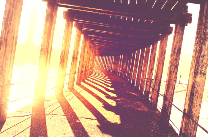 Covered pier pathway with sunshine behind it