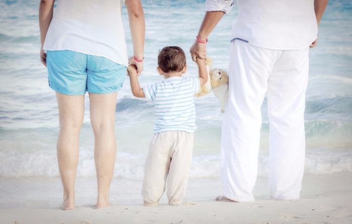couple at beach holding hands with child